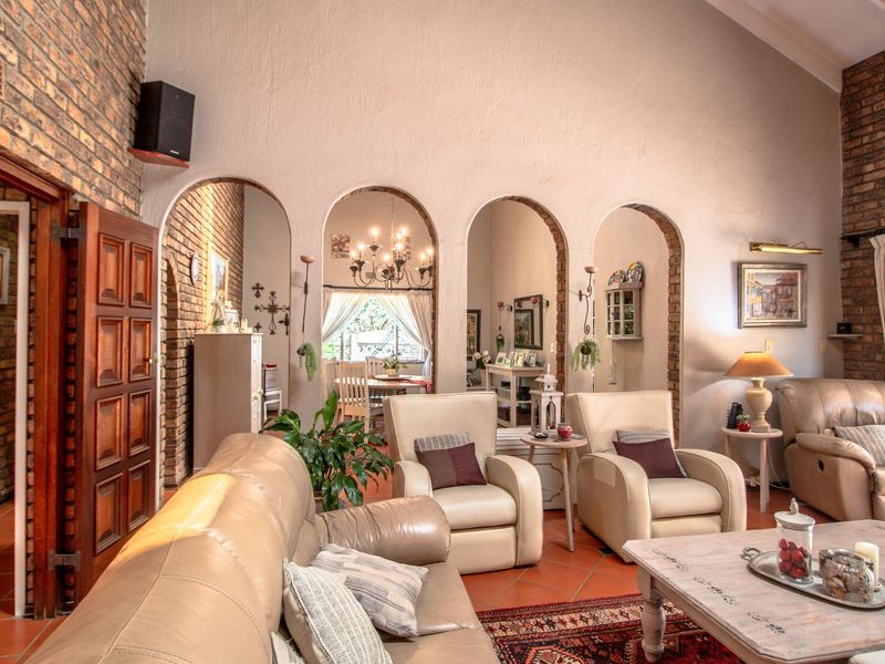 Spacious living room featuring high vaulted ceilings, exposed brick walls, and distinctive arched doorways leading to the dining area, finished with terracotta floor tiles.