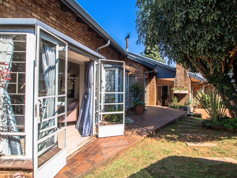 Rear view of the property featuring a brick facade, paved patio area, and access to the interior through multiple sets of french doors.