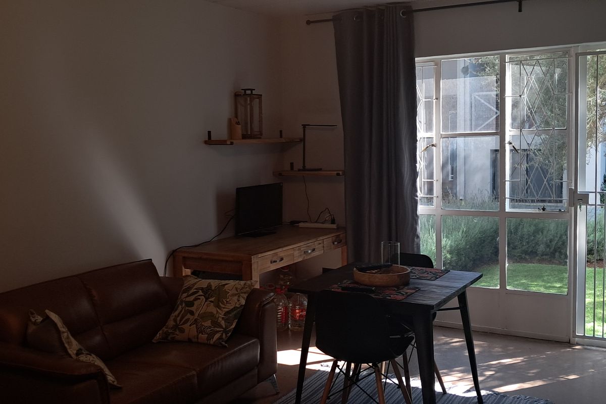 A living area featuring large glass sliding doors with security gates, providing direct access to a garden space.