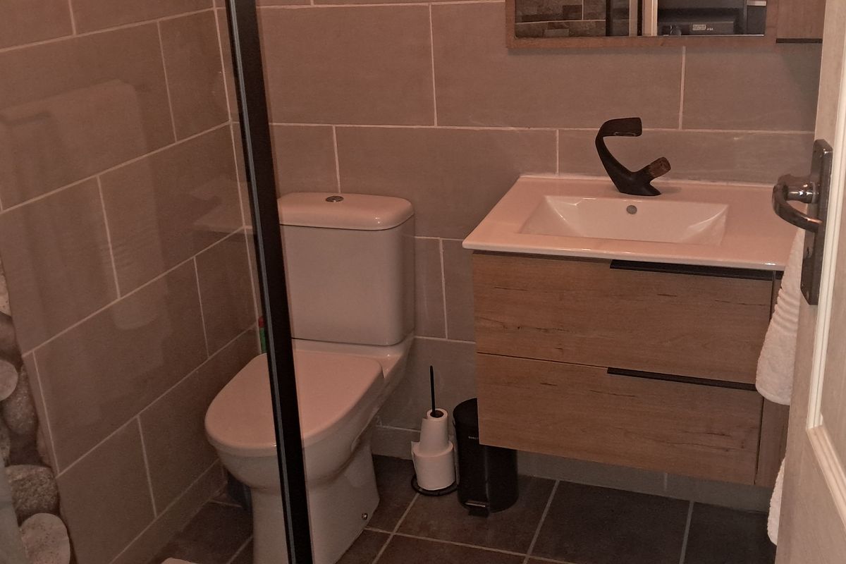 Modern bathroom featuring a wall-mounted vanity with integrated basin, contemporary tapware, a close-coupled toilet, and tiled shower enclosure.