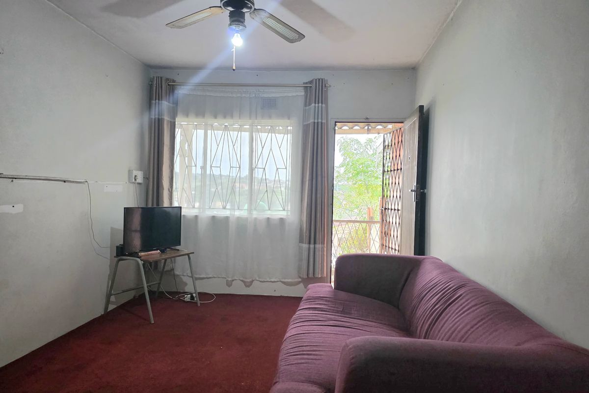 A living room featuring a ceiling fan, security gate, and burglar bars, with direct access to an outdoor area.