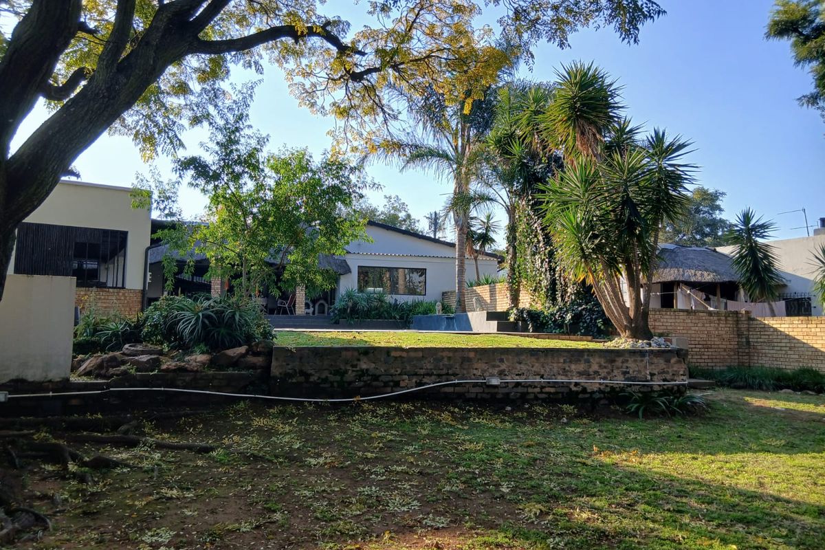 A view of the rear garden featuring a raised lawn area, mature trees, and brick boundary walls, providing a private outdoor space.