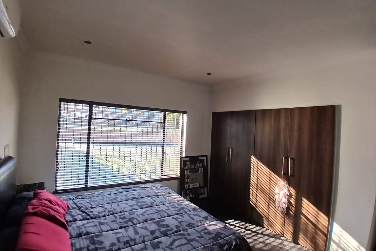 A well-lit bedroom featuring built-in wooden cupboards, recessed downlighting, and venetian blinds, providing a functional and comfortable living space.