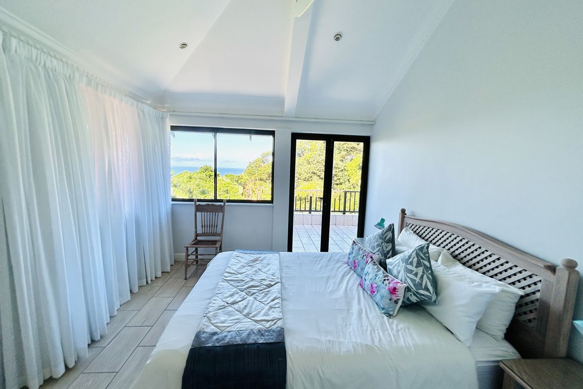 Bright bedroom featuring vaulted ceilings, tiled flooring, and direct access to a private balcony with scenic views.