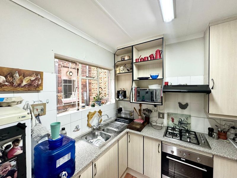 Compact kitchen featuring laminate cabinetry, gas hob, built-in oven, extractor fan, and double bowl sink with tiled splashback.