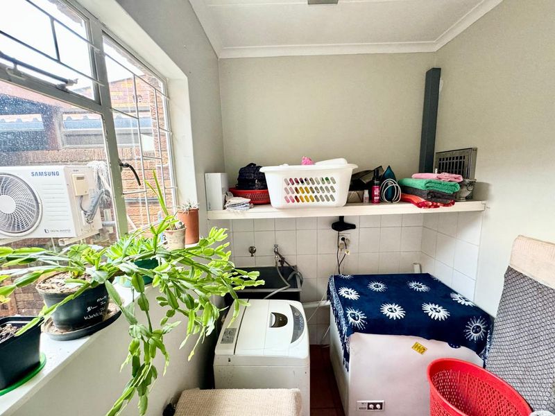 A functional laundry area featuring a tiled splashback, built-in shelving, and plumbing connections, providing a practical space for household utility tasks.