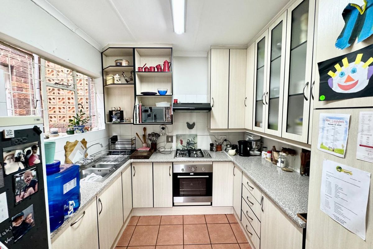 Functional U-shaped kitchen featuring light-toned cabinetry, granite-look laminate countertops, a gas hob, built-in oven, and tiled flooring.
