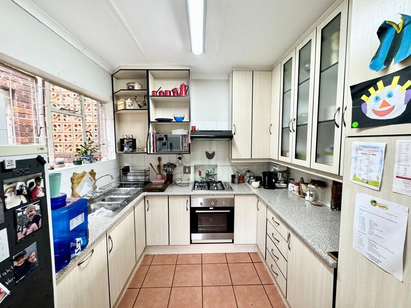 Functional U-shaped kitchen featuring light-toned cabinetry, granite-look laminate countertops, a gas hob, built-in oven, and tiled flooring.