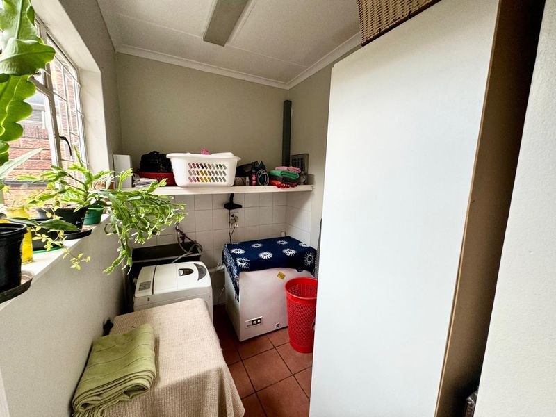 A functional laundry room featuring tiled flooring, built-in shelving, and dedicated plumbing connections for appliances.