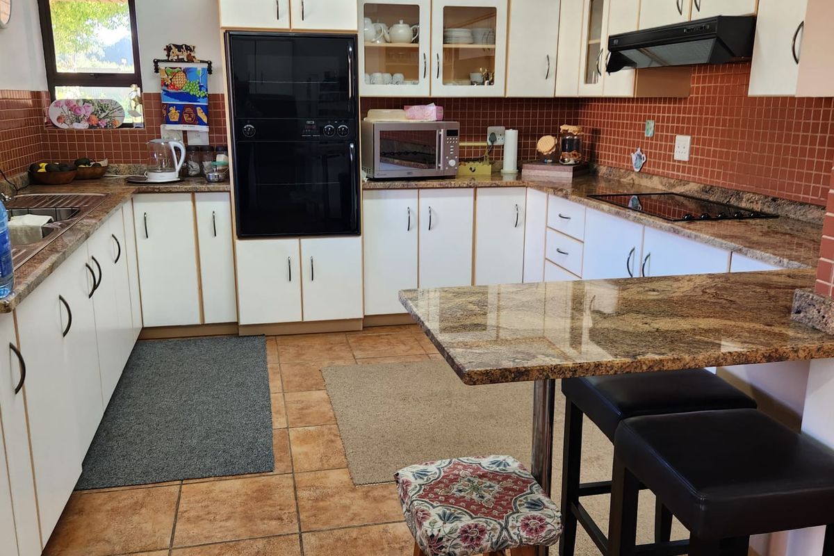 A functional kitchen featuring granite countertops, built-in cabinetry, a ceramic hob, and an integrated oven with a tiled backsplash and flooring.