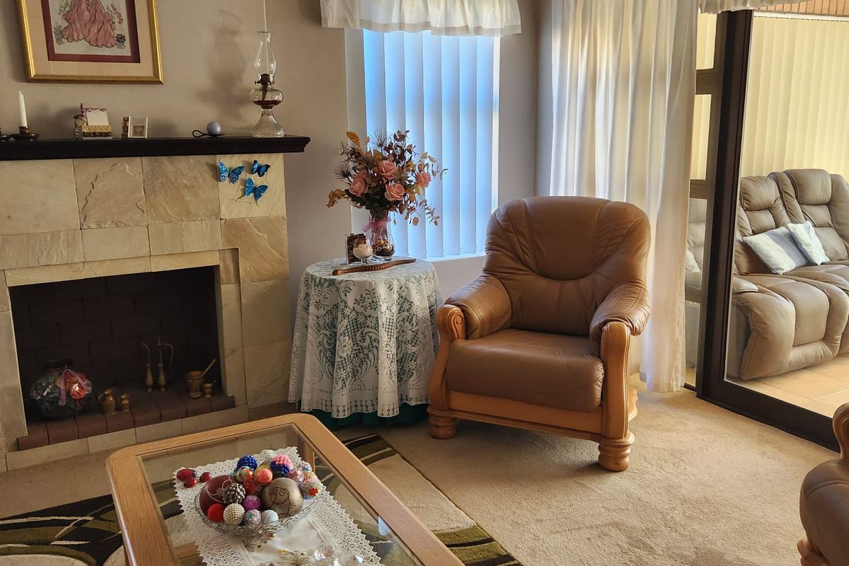 A cozy living room featuring a stone fireplace and large sliding glass doors that provide natural light and access to the patio area.