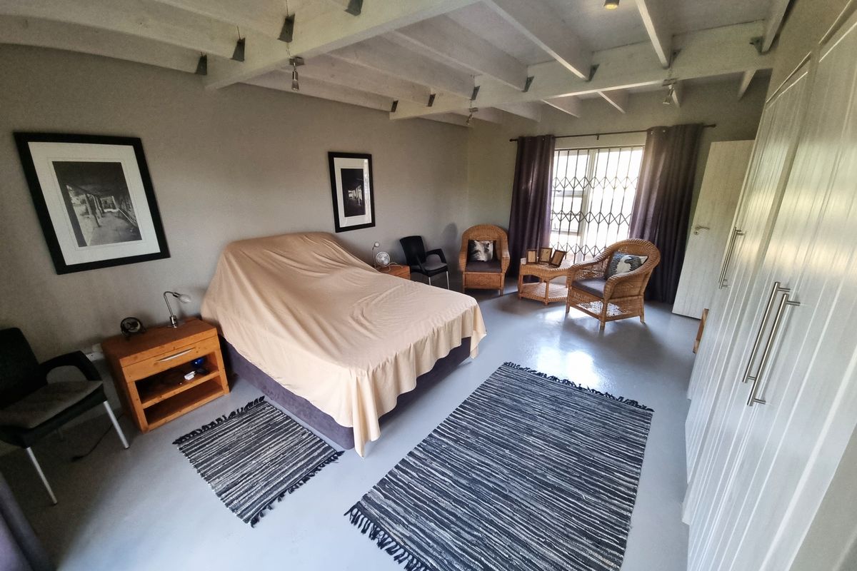 Spacious bedroom featuring exposed timber ceiling beams, a built-in wardrobe, and a window fitted with a security gate.