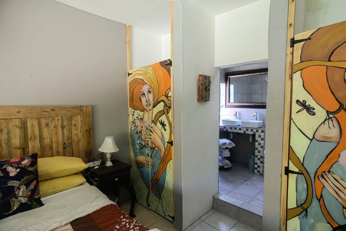 Bedroom featuring an en-suite bathroom with a double vanity, tiled flooring, and custom-painted built-in cupboard doors.
