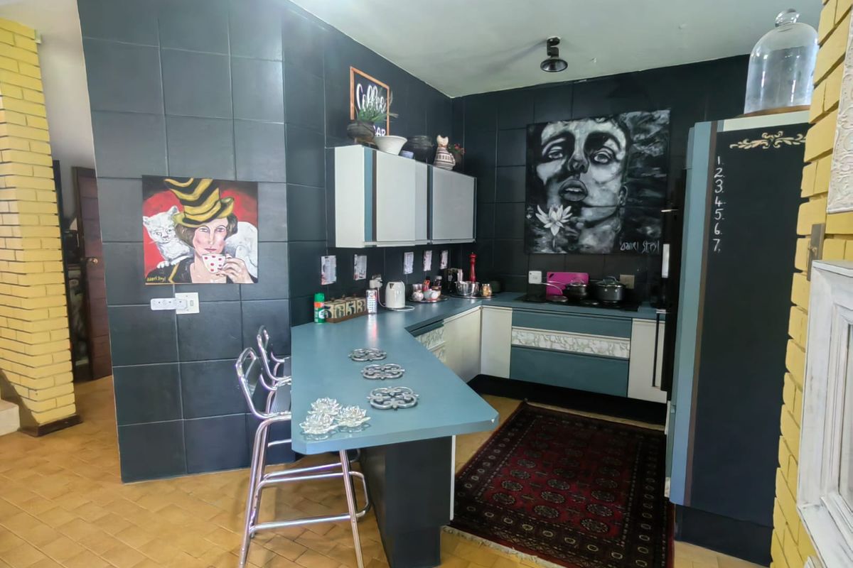 A kitchen featuring dark tiled walls, built-in cabinetry, and a breakfast bar counter, offering a distinct and functional cooking and dining space.