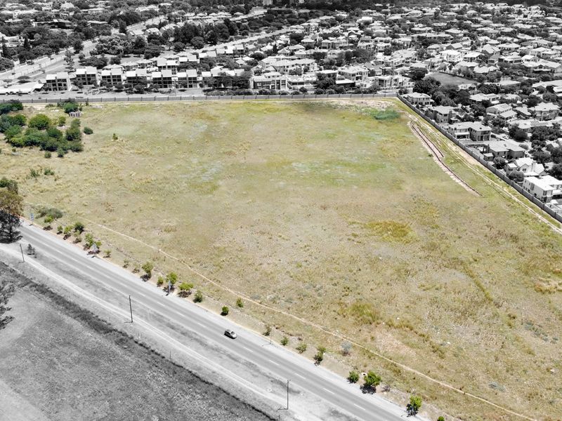 An aerial view of a large, undeveloped residential plot situated in a developed suburban area, offering significant potential for future construction.