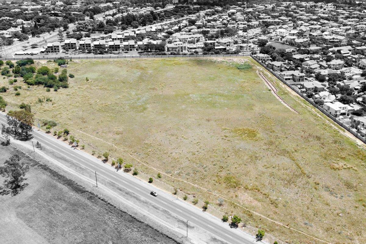 An aerial view of a large, undeveloped residential plot situated in a developed suburban area, offering significant potential for future construction.