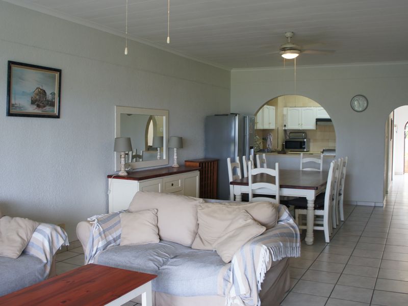 Open plan living and dining area featuring tiled floors, a ceiling fan, and an arched opening leading to the kitchen.