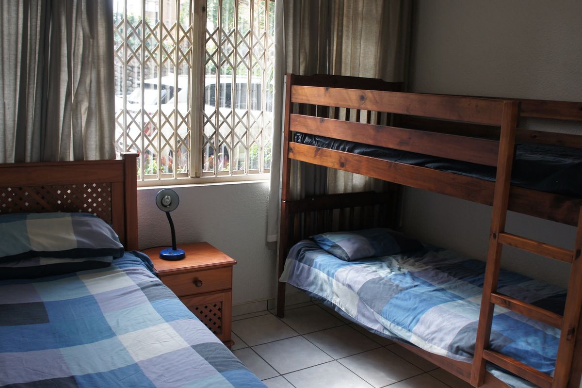 A bedroom featuring tiled flooring and a window fitted with a security gate.