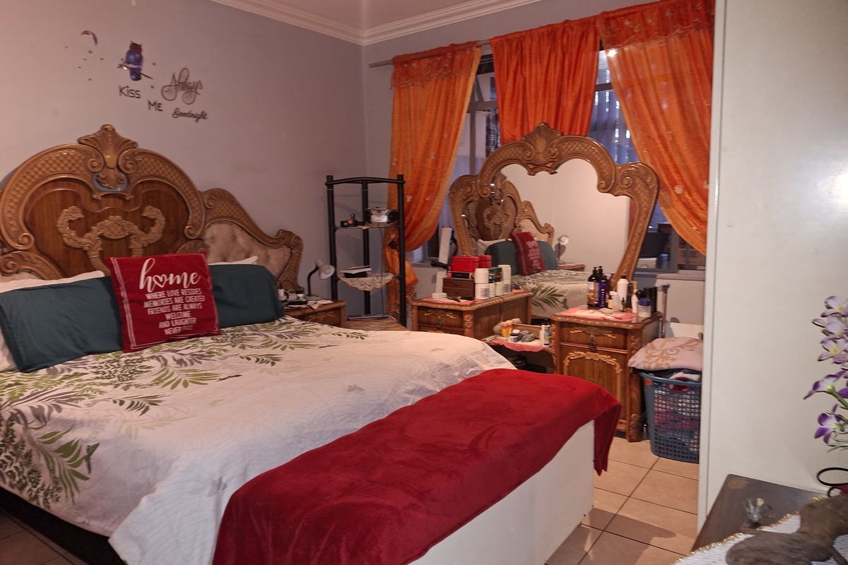A spacious bedroom featuring tiled flooring, built-in cabinetry, and large windows with curtains, offering a comfortable and functional living space.