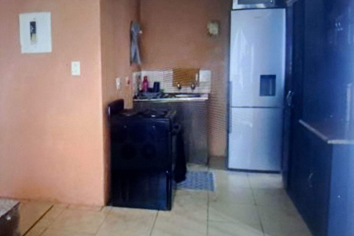 A compact kitchen area featuring tiled flooring, built-in cabinetry, and a freestanding stove, requiring cosmetic updates to improve its overall aesthetic and functionality.