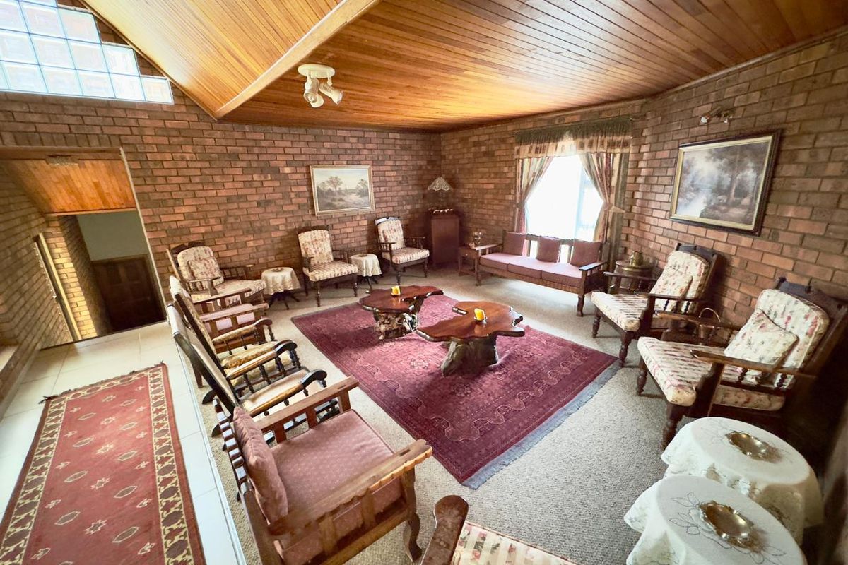 Spacious living room featuring exposed brick walls, a high timber-clad vaulted ceiling, and a unique glass block feature window.