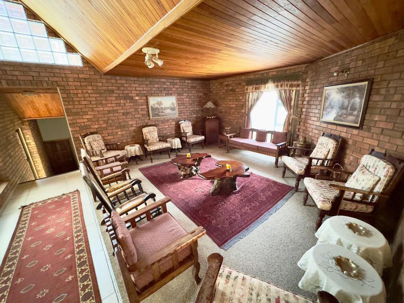 Spacious living room featuring exposed brick walls, a high timber-clad vaulted ceiling, and a unique glass block feature window.
