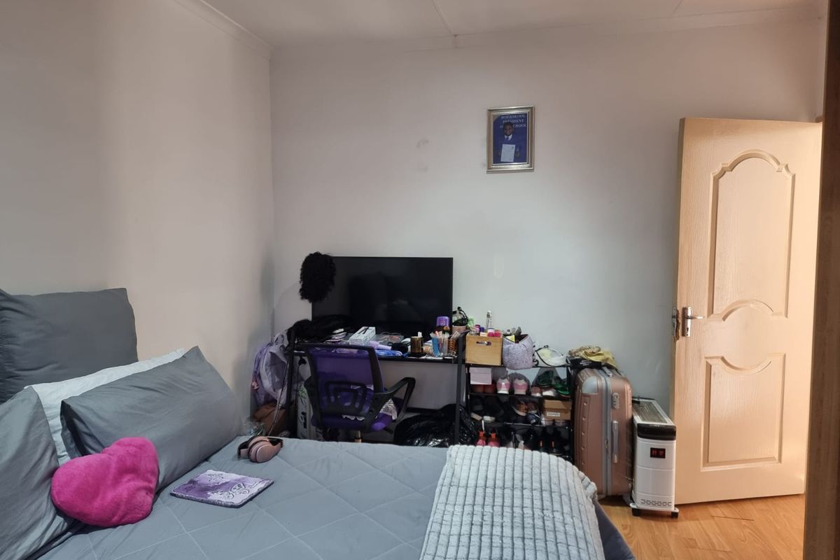 A bedroom featuring laminate flooring and a standard interior door, providing a functional living space.