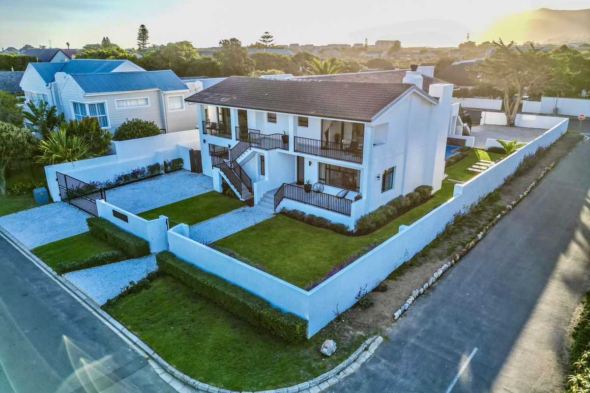 Aerial view of a two-story residential property featuring a tiled roof, balconies, landscaped lawn, and secure boundary walls.
