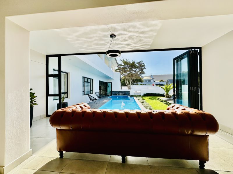 Modern open-plan living space featuring large bi-fold doors that open onto a private swimming pool and landscaped garden area.