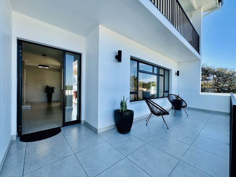 A modern, spacious balcony featuring large format floor tiles, black metal railings, and seamless access to the interior living space.