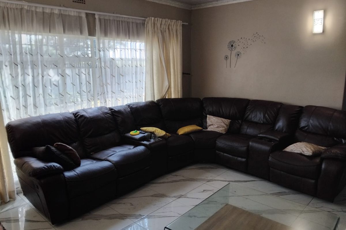 A comfortable living room featuring large windows, modern marble-look floor tiles, and decorative wall lighting, providing a bright and functional space.