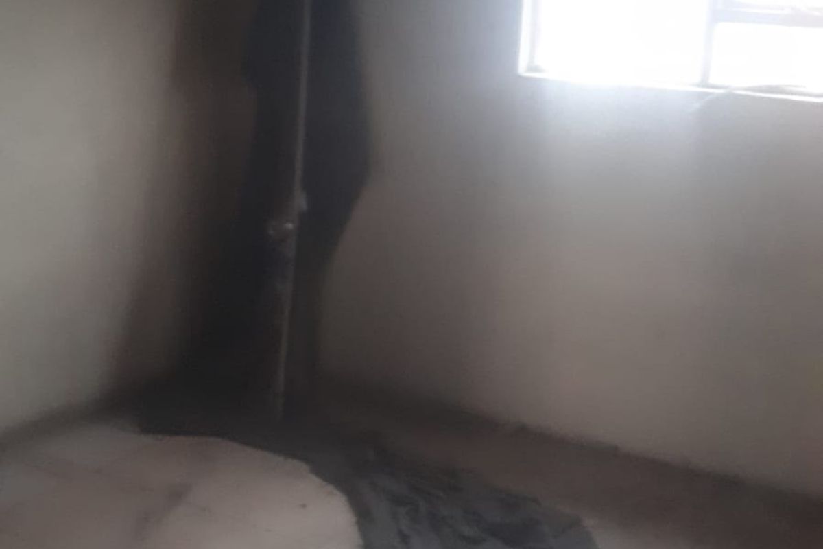 An empty bedroom featuring tiled flooring and a window, requiring cosmetic updates and repairs to the wall surfaces.