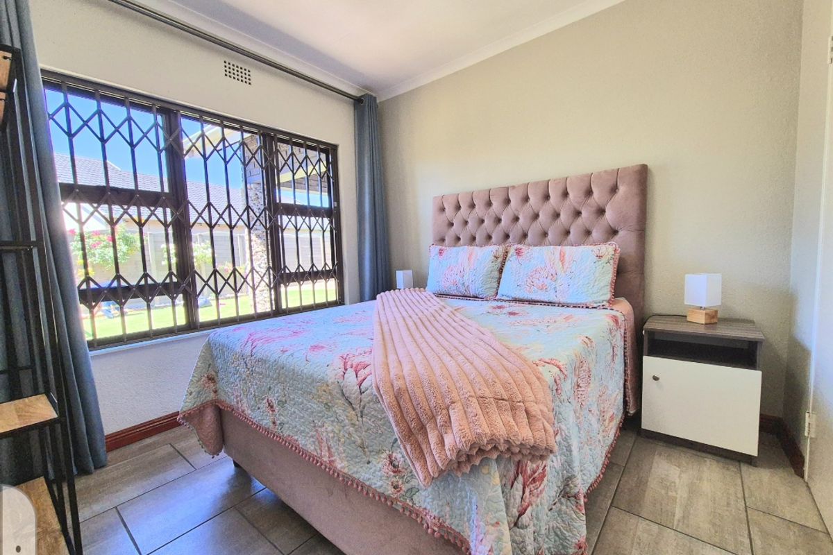 A bedroom featuring tiled flooring and a large window with an integrated security gate.