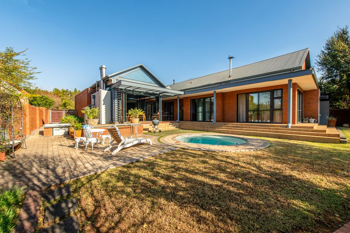 Spacious rear exterior featuring a brick facade, paved patio area, built-in swimming pool, and covered terrace with large glass sliding doors.