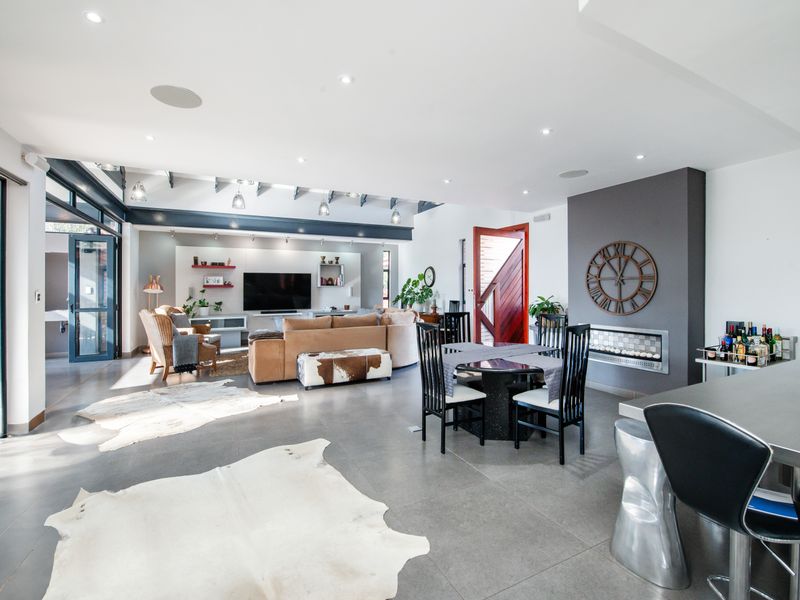 Spacious open-plan living and dining area featuring large format floor tiles, a modern built-in fireplace, and seamless access to the outdoor patio.
