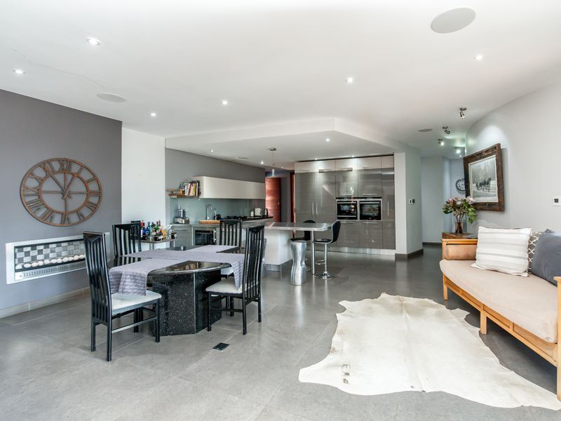 Spacious open-plan living and dining area featuring a modern kitchen with integrated appliances, sleek cabinetry, and recessed ceiling lighting.
