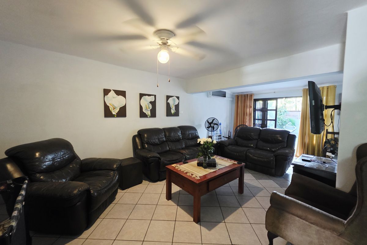 Spacious living room featuring ceramic floor tiles, a ceiling fan, and direct access to the outdoor area through a sliding glass door.