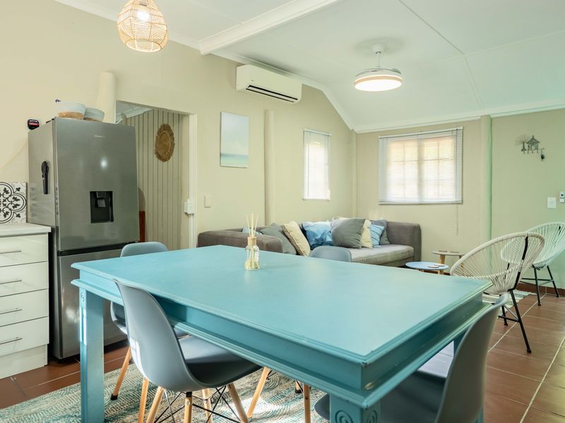 An open-plan living and dining area featuring tiled flooring, split-system air conditioning, and neutral wall finishes with direct access to an outdoor space.