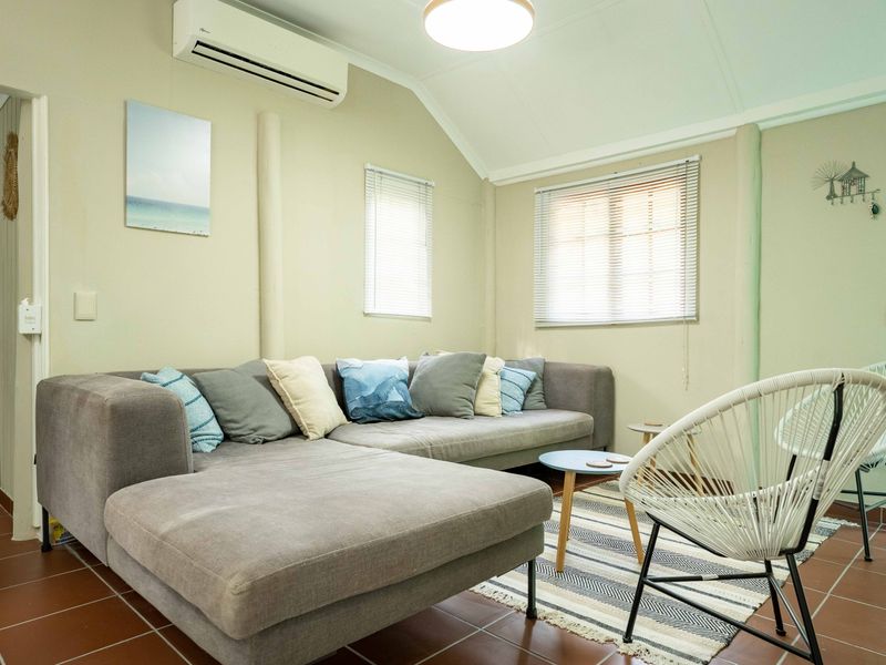 A comfortable living room featuring tiled flooring, a vaulted ceiling, and a wall-mounted split-system air conditioner.