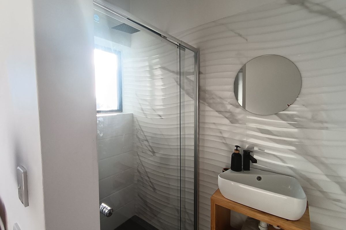 Modern bathroom featuring a glass-enclosed shower with a rain shower head and a stylish vessel sink with a contemporary black faucet.