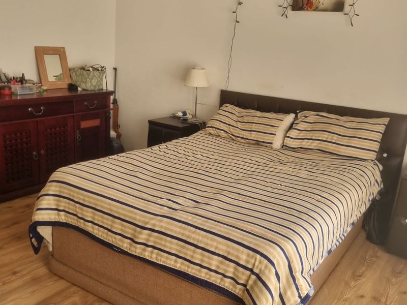 A bedroom featuring light-toned laminate flooring and neutral wall finishes, providing a functional space for rest.