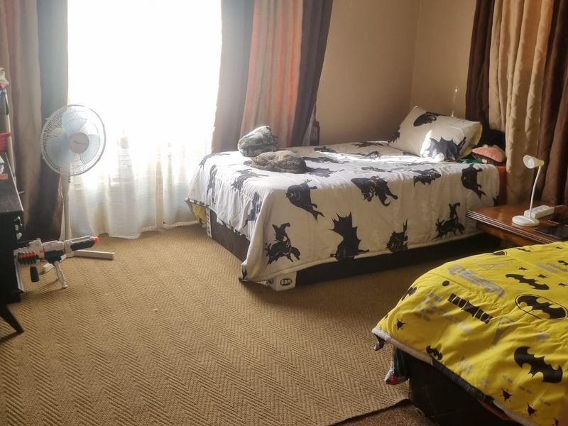 A bedroom featuring carpeted flooring and large windows with curtain rods, providing a functional space for rest.