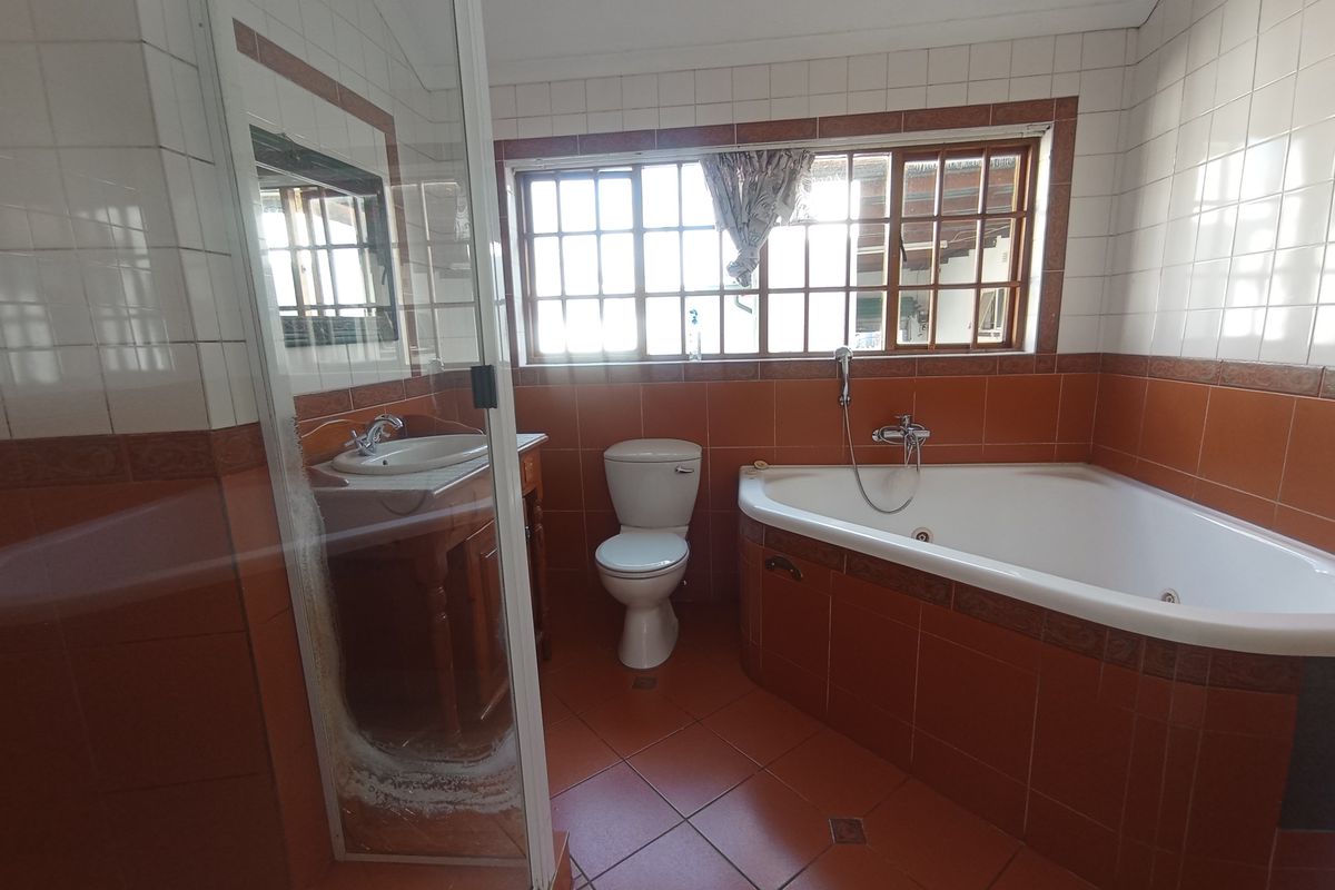A functional bathroom featuring a corner bathtub, separate shower enclosure, vanity basin, and toilet with classic tiled finishes.
