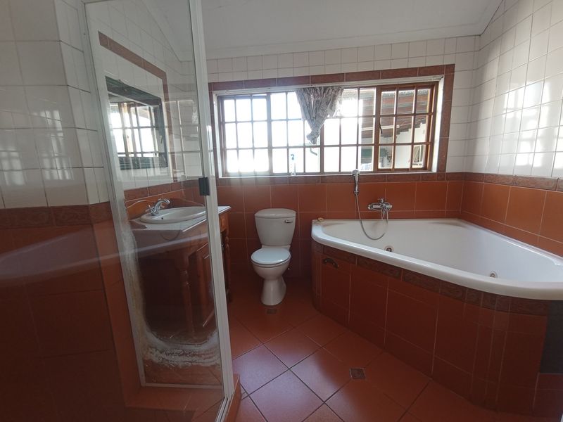 A functional bathroom featuring a corner bathtub, separate shower enclosure, vanity basin, and toilet with classic tiled finishes.
