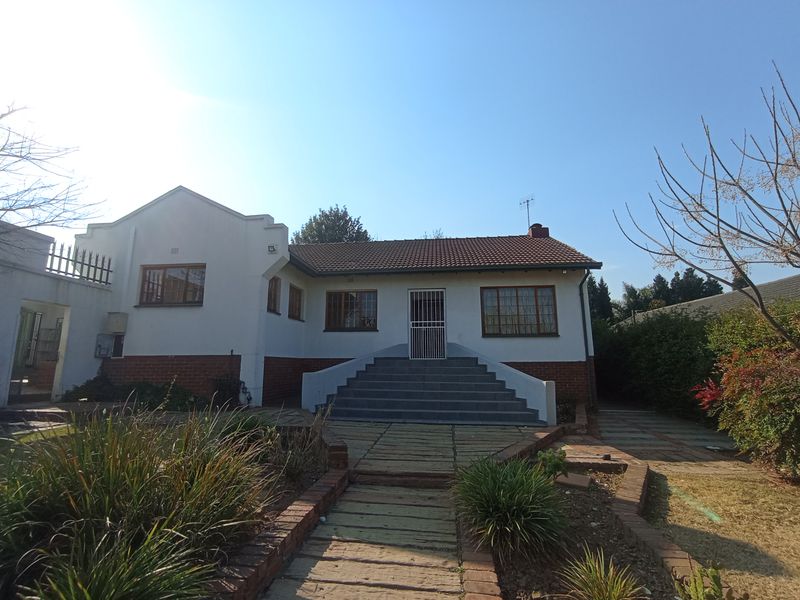 Rear view of a single-story house featuring a tiled roof, brick base, and a central concrete staircase leading to the main entrance.