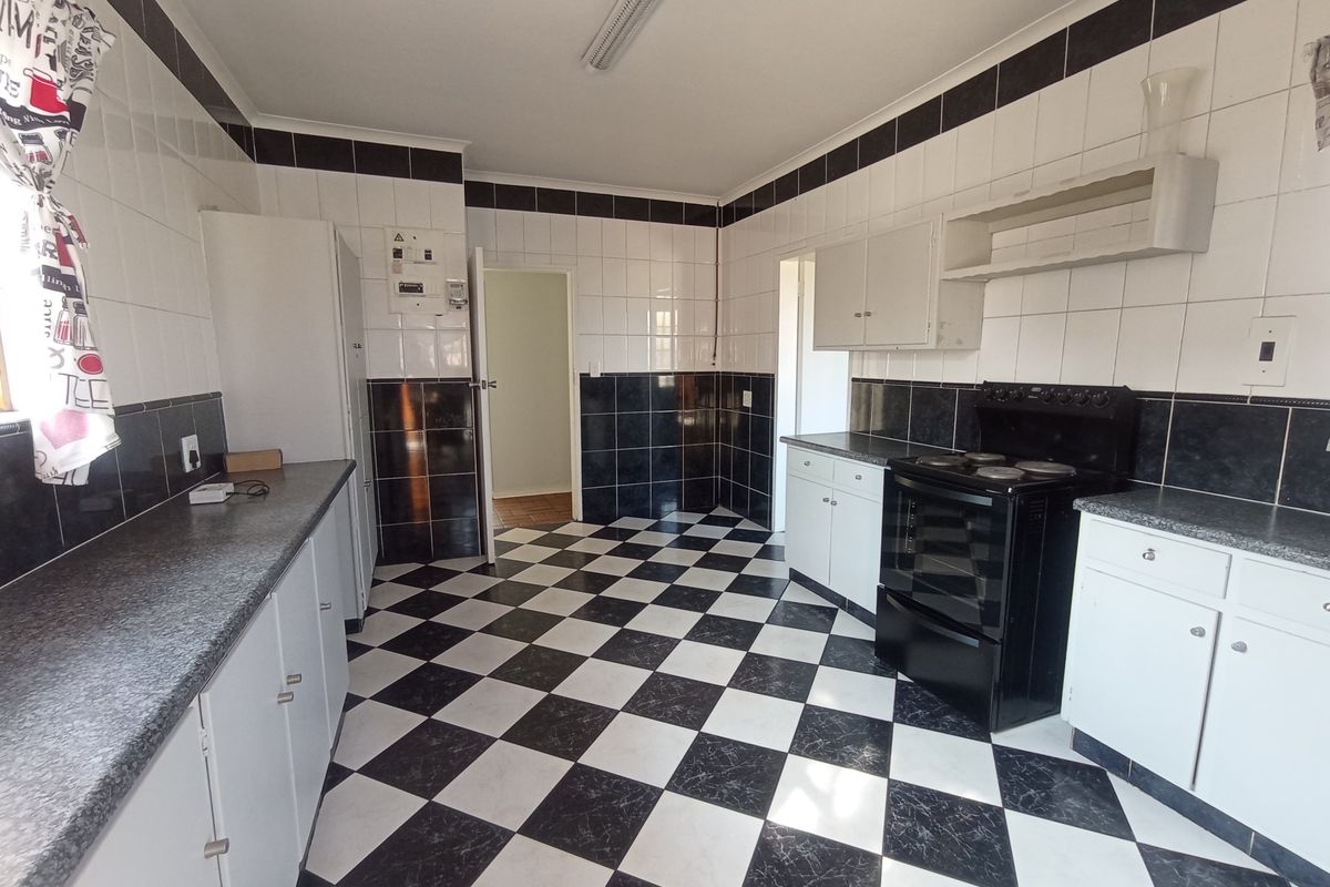 A functional kitchen featuring a classic black and white checkerboard tile theme, built-in cabinetry, and a freestanding electric stove.