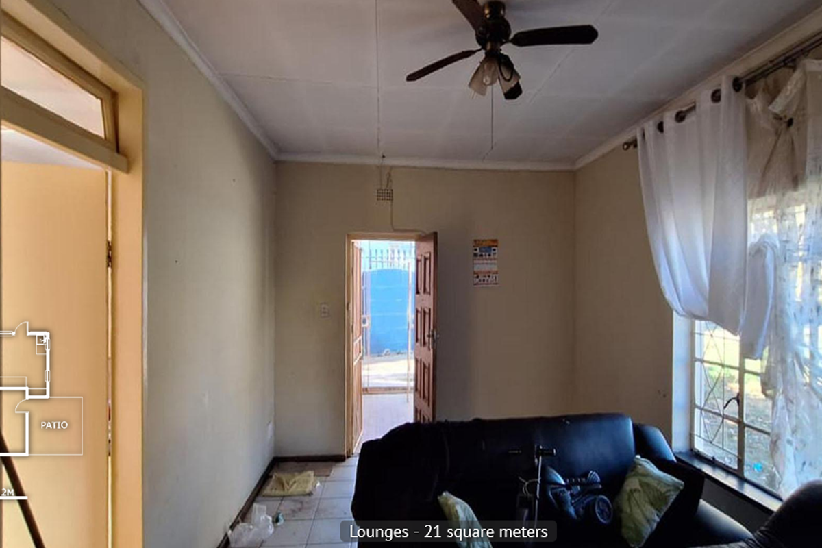 A living room featuring tiled flooring, a ceiling fan, and security bars on the windows, with direct access to an exterior entrance.