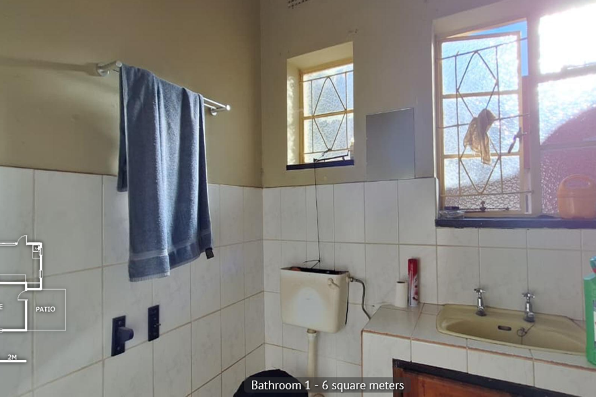 A functional bathroom featuring tiled walls, a built-in vanity with basin, and a wall-mounted toilet cistern, requiring cosmetic updates.