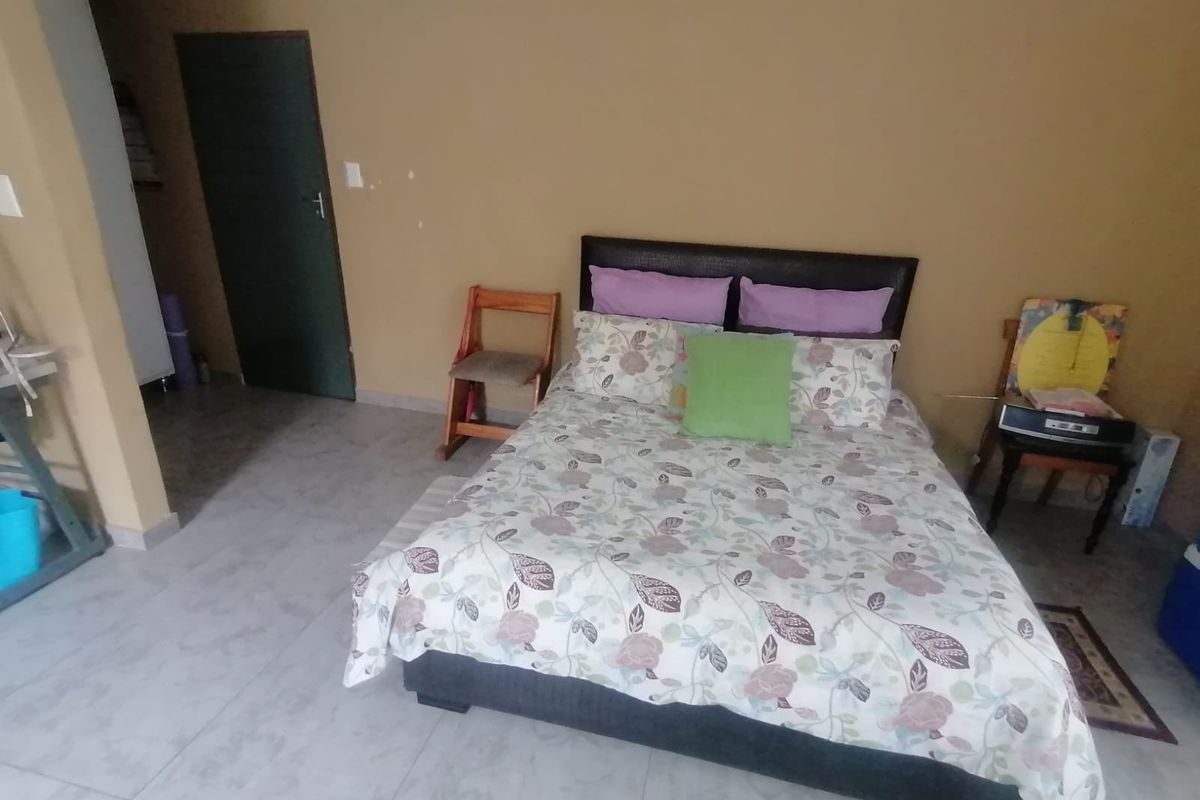 A functional bedroom featuring tiled flooring and neutral wall finishes, providing a simple and practical living space.