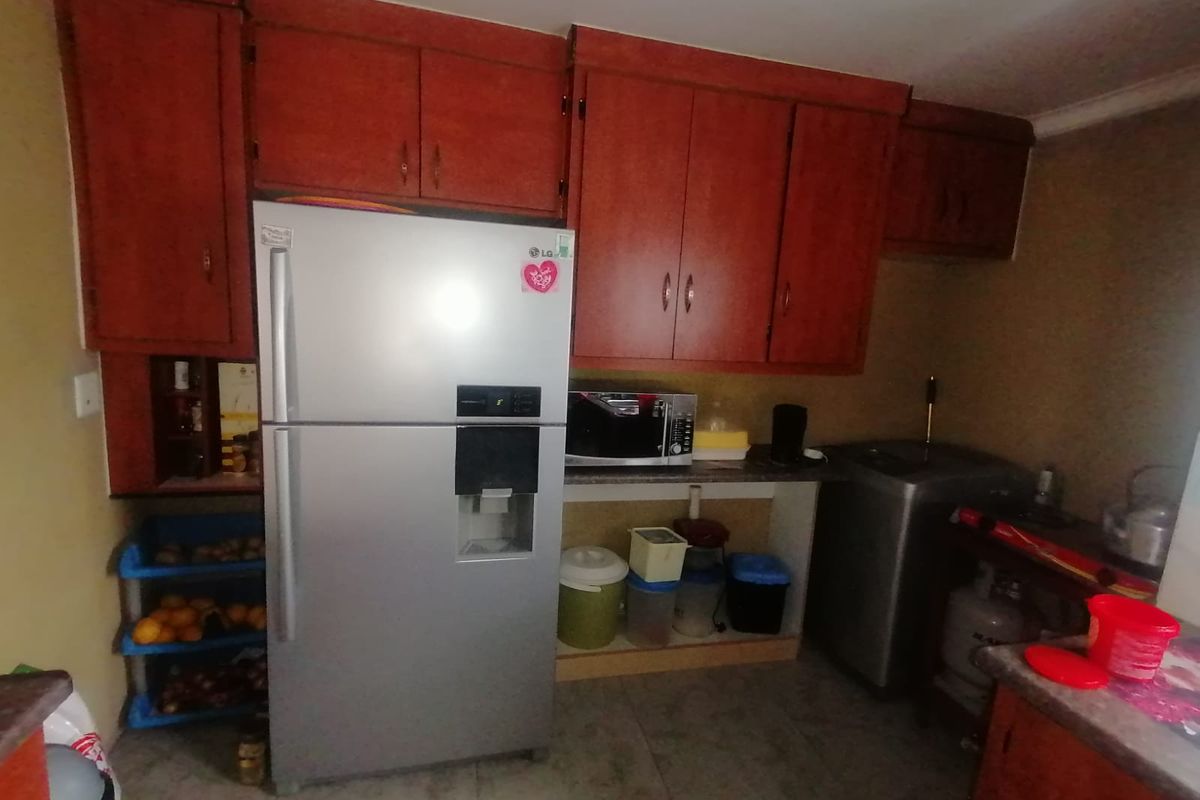 A functional kitchen area featuring built-in wooden cabinetry and tiled flooring, offering a practical layout for daily food preparation and storage.